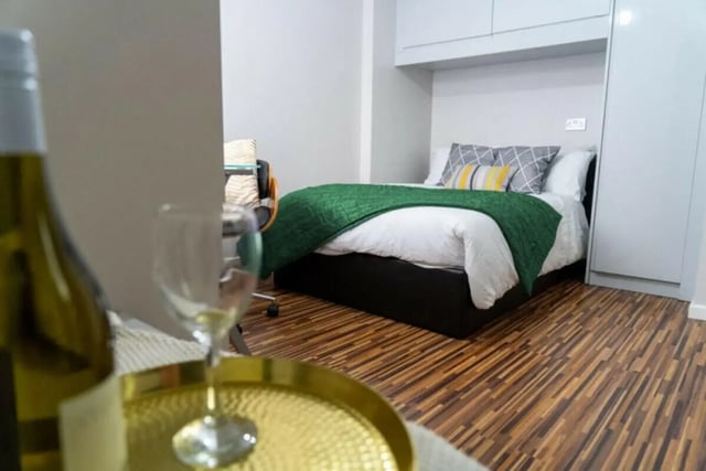 Bed with green blanket pillows and desk bedroom at 6 Bedroom House at 5, ASHFIELD ROAD in Manchester Student Accommodation