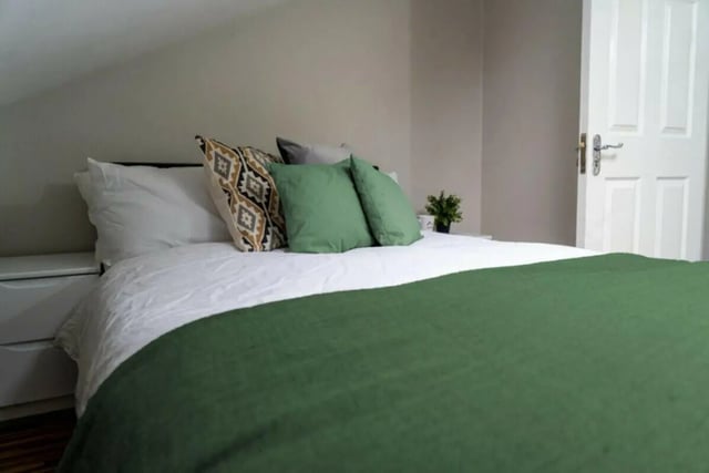 Bed with green blanket pillows and white sheets bedroom at 6 Bedroom House at 5, ASHFIELD ROAD in Manchester Student Accommodation