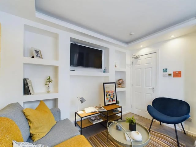 Gray sofa yellow pillows mounted TV shelves living room at 6 Bedroom House at 174, ACOMB STREET in Manchester Student Accommodation