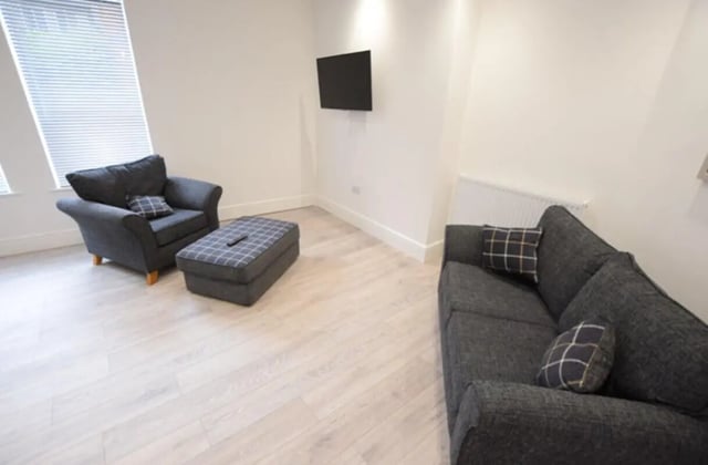 Dark grey sofa armchair ottoman with plaid pillows living room at 10 Bedroom House at 15, Monks Road in Lincoln Student Accommodation