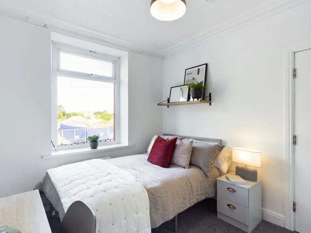 Bed with red pillows nightstand lamp artwork bedroom at 5 Bedroom House at 17, Gladstone Terrace in Lancaster Student Accommodation