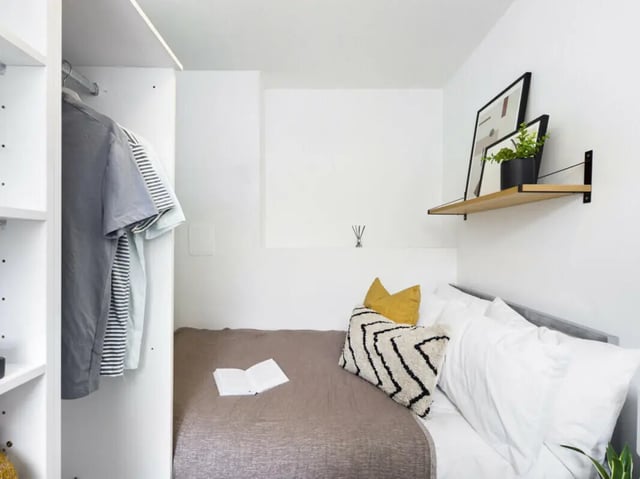Bed with pillows shelf with art and clothes bedroom at 5 Bedroom House at 17, Gladstone Terrace in Lancaster Student Accommodation