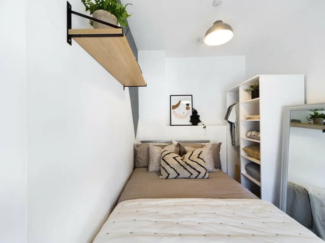 Bed with patterned pillows shelf closet mirror bedroom at 5 Bedroom House at 17, Gladstone Terrace in Lancaster Student Accommodation