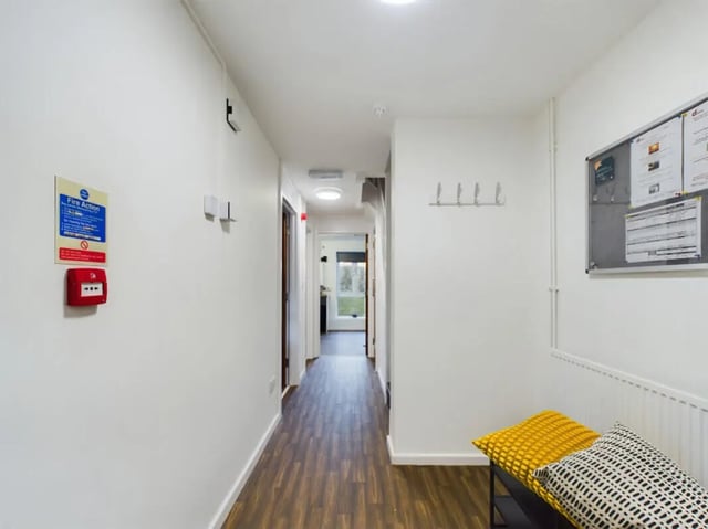 Hallway with fire alarm bench cushions bulletin board hallway at 6 Bedroom House at 1, Brookside in Derby Student Accommodation