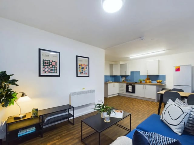 Modern kitchen living area with white cabinets and blue accents at 3 Bedroom House at 20, Brookside in Derby Student Accommodation