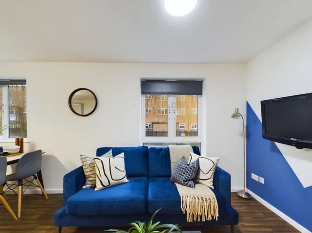 Blue sofa with pillows wall mounted television living room at 3 Bedroom House at 20, Brookside in Derby Student Accommodation