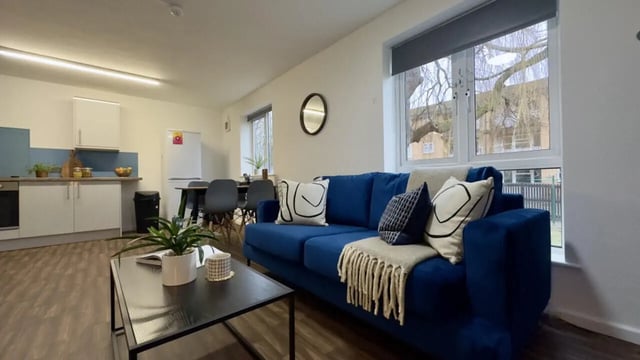 Blue sofa with throw pillows living area kitchen at 3 Bedroom House at 20, Brookside in Derby Student Accommodation
