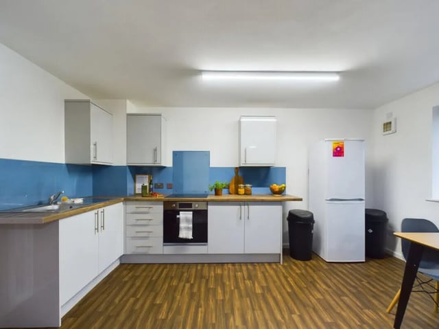 White cabinets fridge oven and blue backsplash kitchen at 3 Bedroom House at 20, Brookside in Derby Student Accommodation