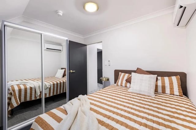 Bed with striped bedding mirrored wardrobe interior bedroom at UKO Redfern in Sydney Student Accommodation