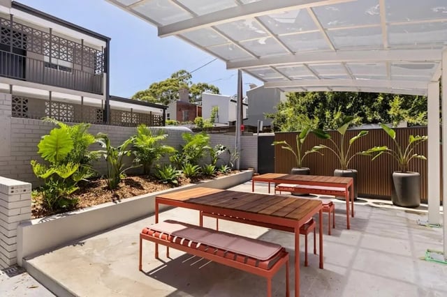 Outdoor seating area with wooden tables and benches patio exterior at UKO Redfern in Sydney Student Accommodation