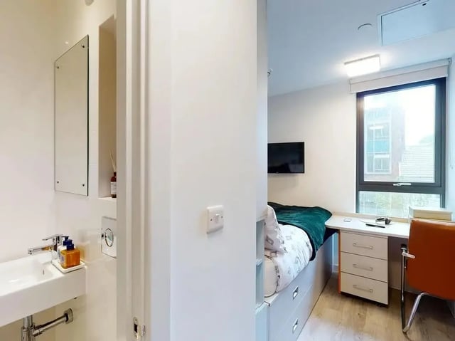 Bed with green blanket desk and chair bedroom at SEREN in Swansea Student Accommodation