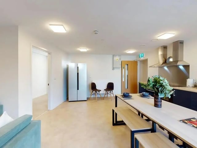 Dining table, benches, fridge, chairs, kitchen area at SEREN in Swansea Student Accommodation