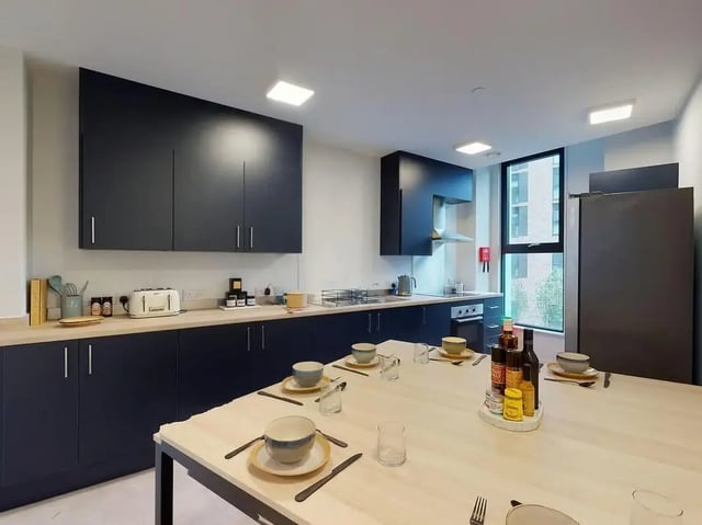 Dark cabinets with a table set for meals kitchen at SEREN in Swansea Student Accommodation