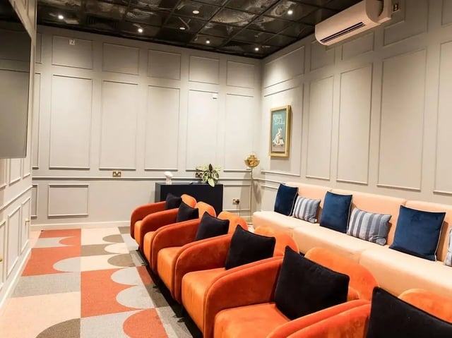 Orange chairs black pillows and peach couch cinema room at SEREN in Swansea Student Accommodation