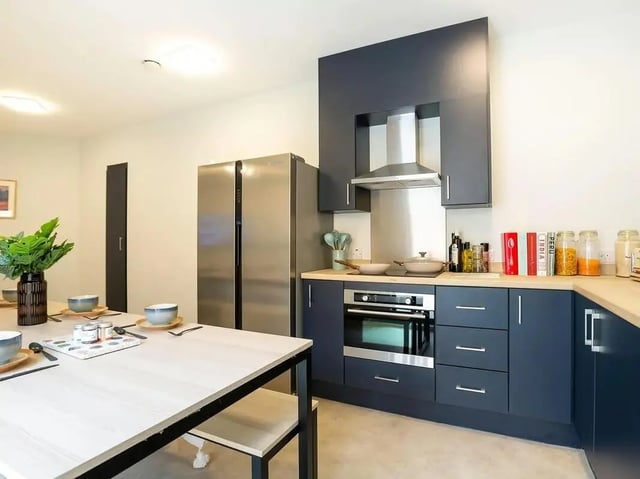 Dining table refrigerator oven cabinets kitchen at SEREN in Swansea Student Accommodation