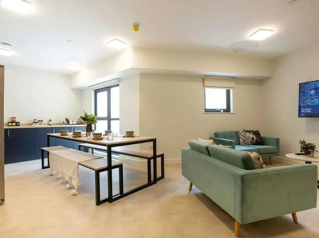 Table, benches, sofas, and TV living room at SEREN in Swansea Student Accommodation