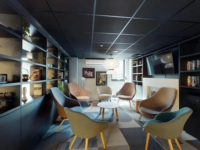 Chairs around coffee table shelves with decor living room at SEREN in Swansea Student Accommodation