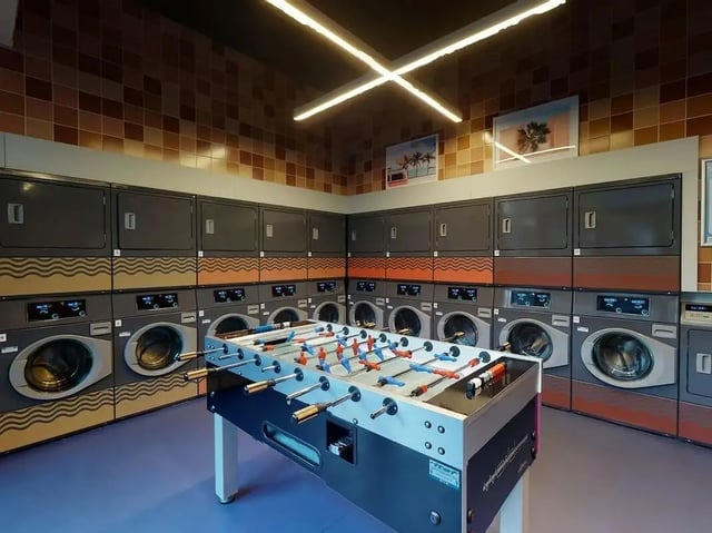 Row of washing machines foosball table laundry room at SEREN in Swansea Student Accommodation