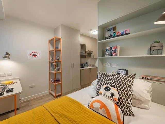 Bed with BB8 pillow shelves and kitchen area bedroom at SEREN in Swansea Student Accommodation