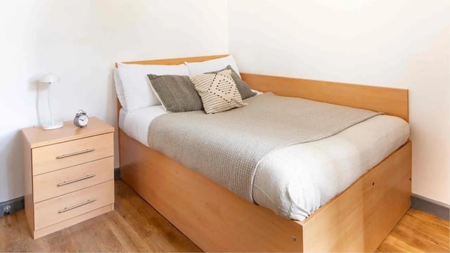 Bed with pillows and blanket nightstand bedroom at Alexandra Hall in Aberystwyth Student Accommodation