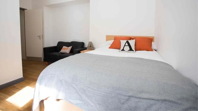 Bed with orange pillows and grey throw bedroom at Alexandra Hall in Aberystwyth Student Accommodation
