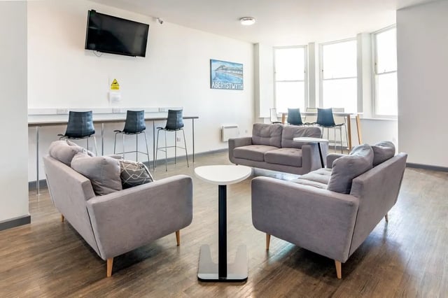 Sofas tables bar stools and TV living room at Alexandra Hall in Aberystwyth Student Accommodation