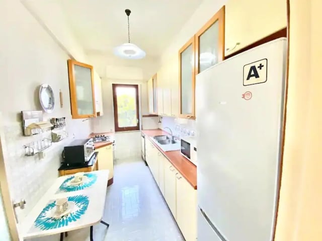 Compact kitchen with small table refrigerator and cabinets kitchen at Appartamento soleggiato con ampia terrazza, giardino e parcheggio in Sant'Agnello Student Accommodation