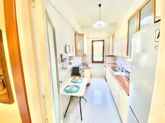 Small kitchen with fridge table and cabinets kitchen at Appartamento soleggiato con ampia terrazza, giardino e parcheggio in Sant'Agnello Student Accommodation