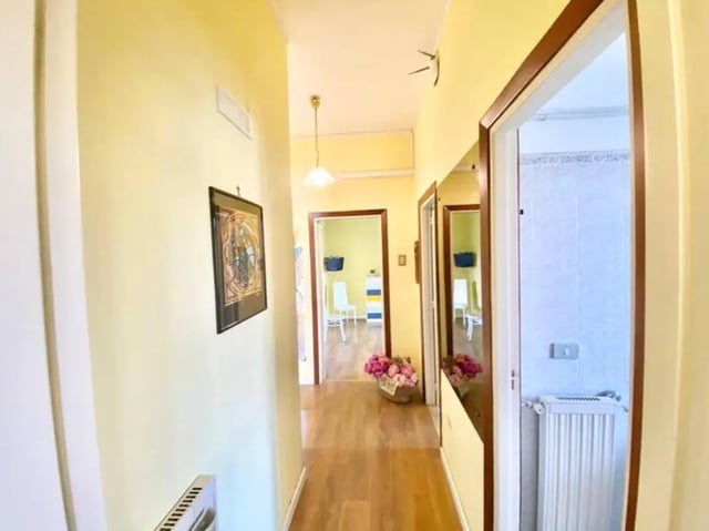 Hallway with framed art vase flowers radiator bathroom at Appartamento soleggiato con ampia terrazza, giardino e parcheggio in Sant'Agnello Student Accommodation