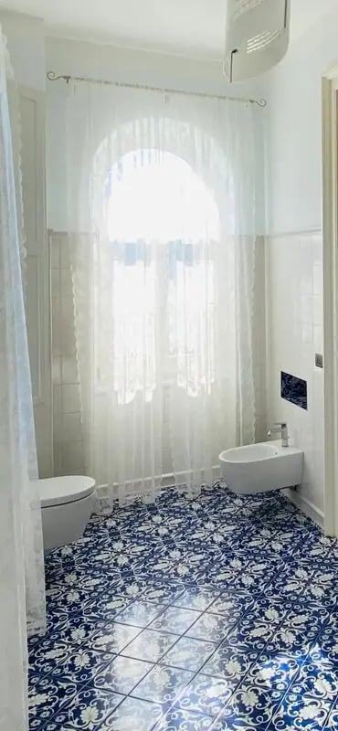 Toilet bidet patterned floor bright window bathroom at Appartamento di due stanze in Sant'Agnello Student Accommodation