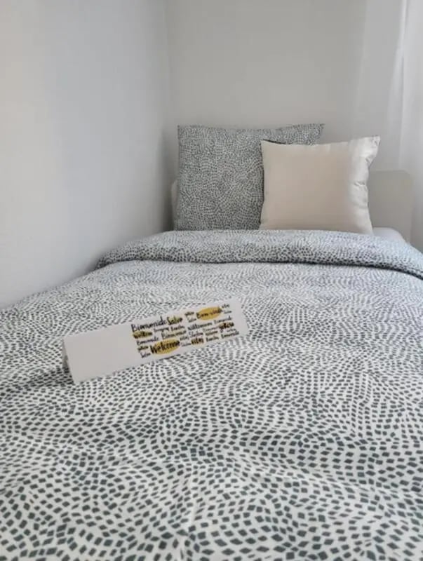 Bed with welcome sign patterned bedding bedroom at Welcoming 2-bedroom apartment in Fundão in Fundão Student Accommodation