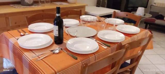 Table set with plates glasses wine dining room at 2-bedroom house, with outdoor area in La Spezia Student Accommodation