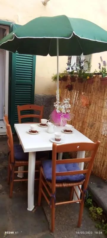 Table and chairs under umbrella outdoor dining area at 2-bedroom house, with outdoor area in La Spezia Student Accommodation