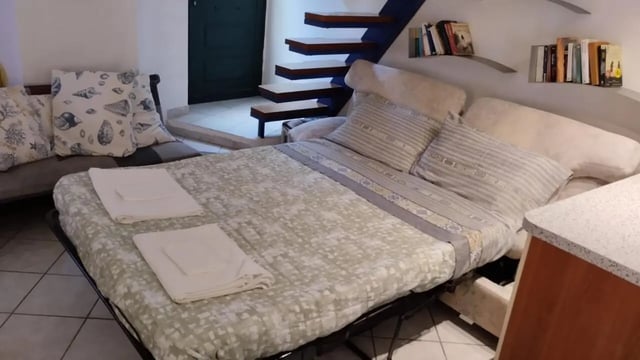 Bed with pillows sofa and stairs living room at 2-bedroom house, with outdoor area in La Spezia Student Accommodation