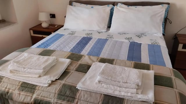Bed with pillows towels and bedside table Bedroom at 2-bedroom house, with outdoor area in La Spezia Student Accommodation