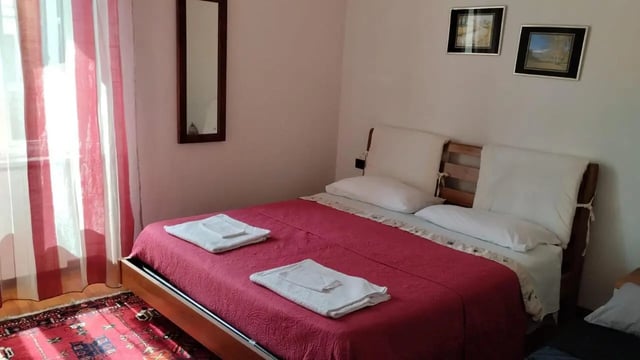 Bed with pink cover towels and paintings Bedroom at 2-bedroom house, with outdoor area in La Spezia Student Accommodation