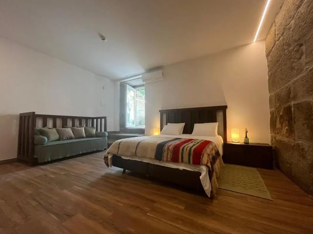 Bed with colorful blanket and sofa bedroom at Spacious Double Bedroom ensuite close to Barragem de Vascoveiro in Guarda Student Accommodation
