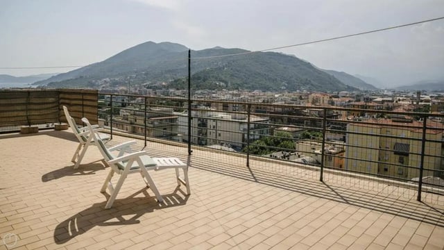 Two white deck chairs on tiled balcony overlooking town Exterior at Welcoming 2-bedroom apartment near the Albenga train station in Albenga Student Accommodation