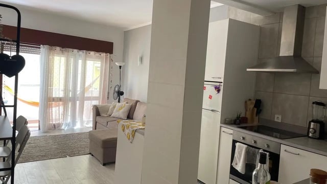 Sofa ottoman fan hammock and kitchen living room at 1-bedroom flat in Armação de Pêra with balcony all electric no Gas in Silves Student Accommodation