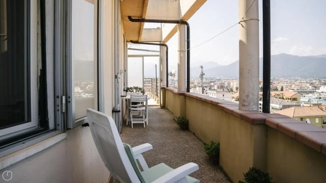 White chair on balcony overlooking cityscape Balcony at Welcoming 2-bedroom apartment near the Albenga train station in Albenga Student Accommodation