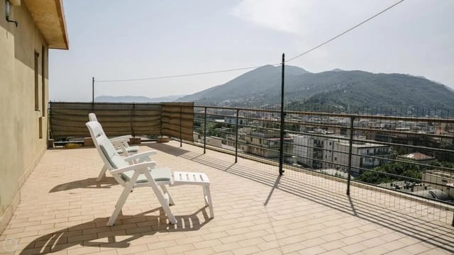 Two white lounge chairs on tiled balcony overlooking town exterior at Welcoming 2-bedroom apartment near the Albenga train station in Albenga Student Accommodation