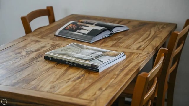 Wooden table with books and chairs dining area at Welcoming 2-bedroom apartment near the Albenga train station in Albenga Student Accommodation