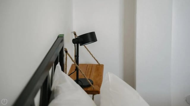Black lamp wooden shelf white pillows bedroom at Welcoming 2-bedroom apartment near the Albenga train station in Albenga Student Accommodation
