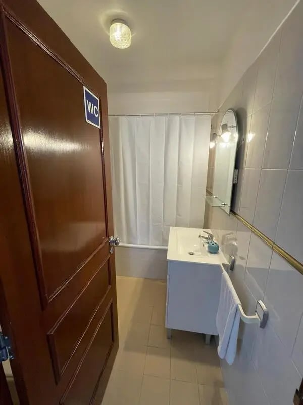 Sink vanity towel rack mirror shower curtain bathroom at Sunny flat very close to the beach in Faro Student Accommodation