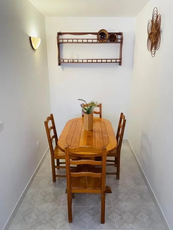 Wooden table and chairs with wall shelf dining area at Sunny flat very close to the beach in Faro Student Accommodation