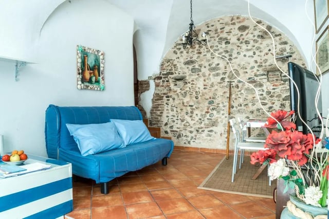 Blue sofa with pillows and a TV living room at Cosy double-bedroom apartment in Albenga (SV) in Albenga Student Accommodation