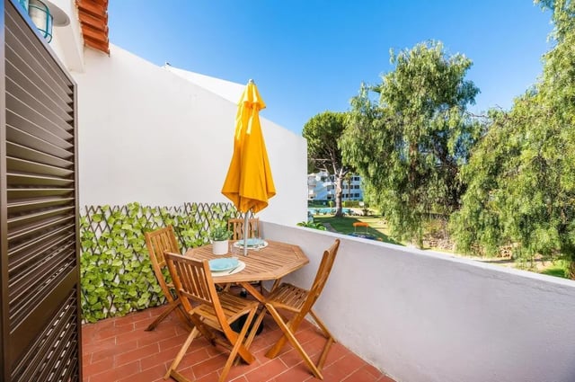 Wooden table chairs yellow umbrella outdoor living area at Luxurious 1-bedroom apartment in Vilamoura in Faro Student Accommodation
