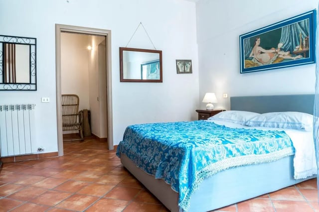 Bed with blue spread near doorway bedroom at Cosy double-bedroom apartment in Albenga (SV) in Albenga Student Accommodation