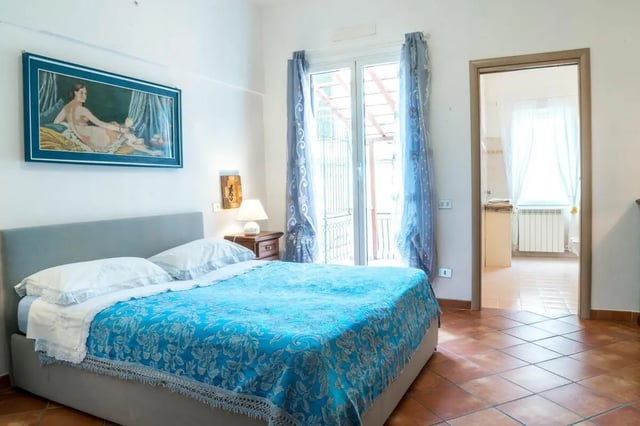 Bed with blue cover and framed artwork Bedroom at Cosy double-bedroom apartment in Albenga (SV) in Albenga Student Accommodation