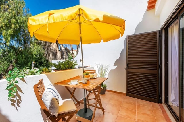 Table umbrella chairs patio tiling exterior at Luxurious 1-bedroom apartment in Vilamoura in Faro Student Accommodation